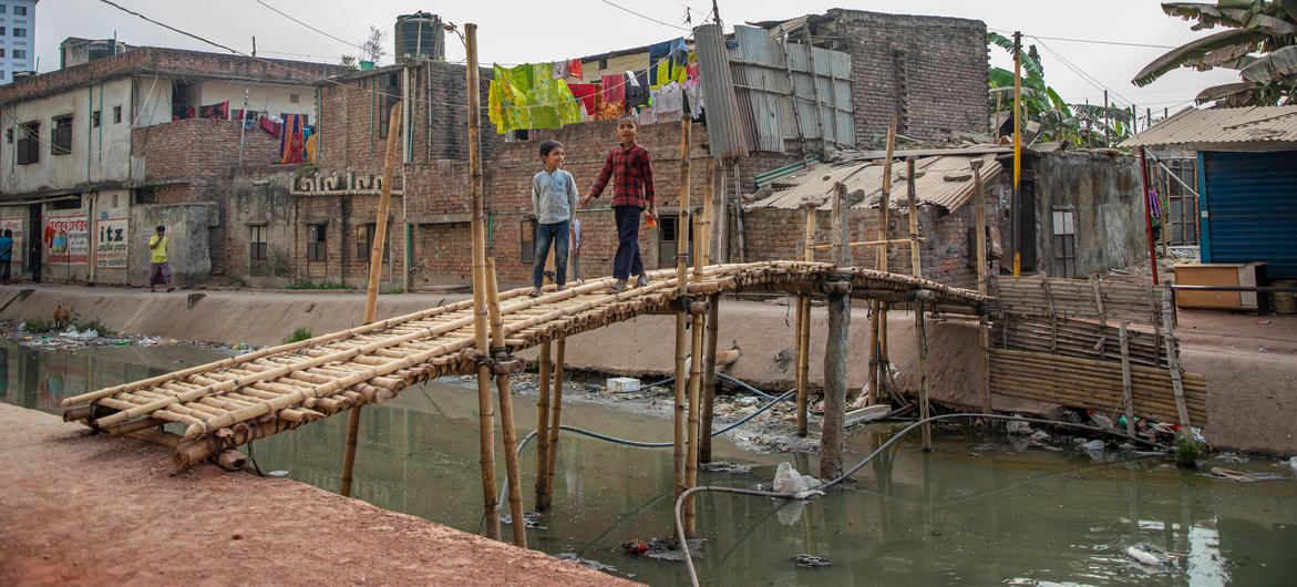 Um canal poluído flui através de uma favela nos arredores de Dhaka, capital de Bangladesh