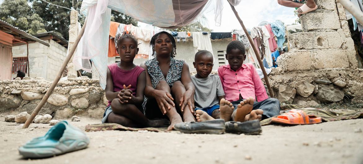 Uma mãe sentada com os filhos num acampamento improvisado em Léogâne, nos arredores da capital haitiana, Porto Príncipe