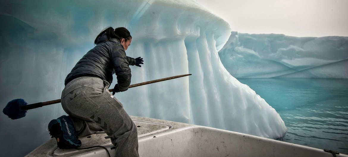 Um pescador tenta evitar que sua rede de pesca seja arrastada por um iceberg no mar da Groenlândia