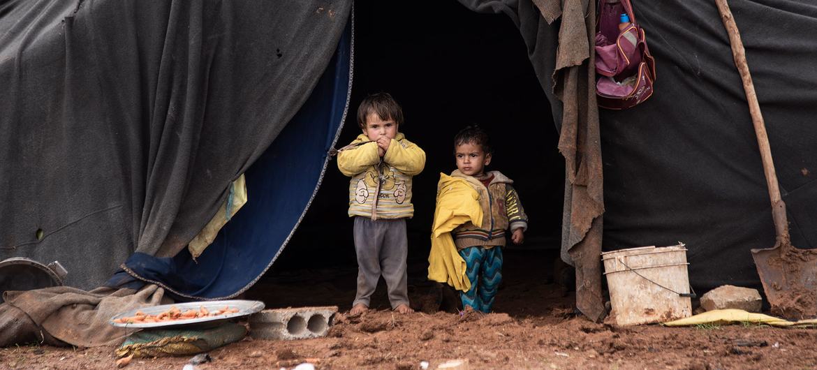 Crianças deslocadas em frente à tenda de sua família em um acampamento informal no sul da Síria.