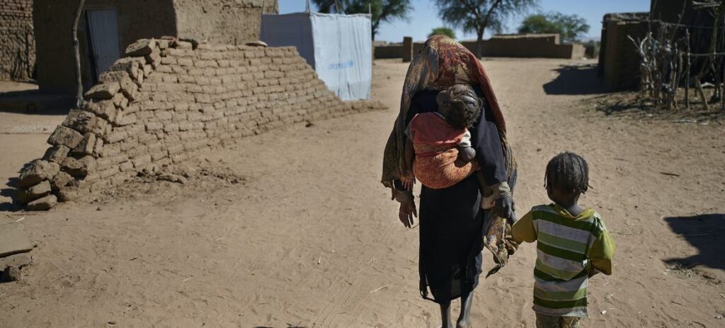 Crianças caminhando para seu abrigo em um campo de deslocados internos perto de El Fasher, capital do Norte de Darfur, Sudão