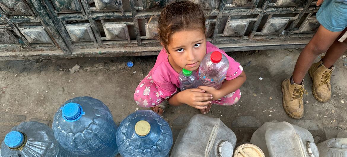 Uma criança espera para encher recipientes de água em Gaza