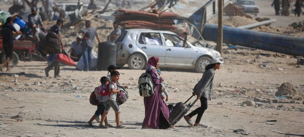 Uma família em Gaza se desloca em um terreno baldio de destruição.