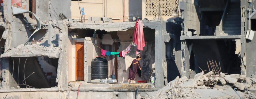 Uma mulher limpa o chão de um edifício destruído em Gaza